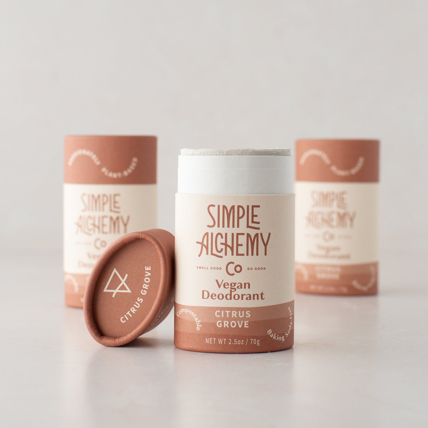 Three compostable tubes of Citrus Grove Natural Deodorant, one with the cap off, on a warm cream background