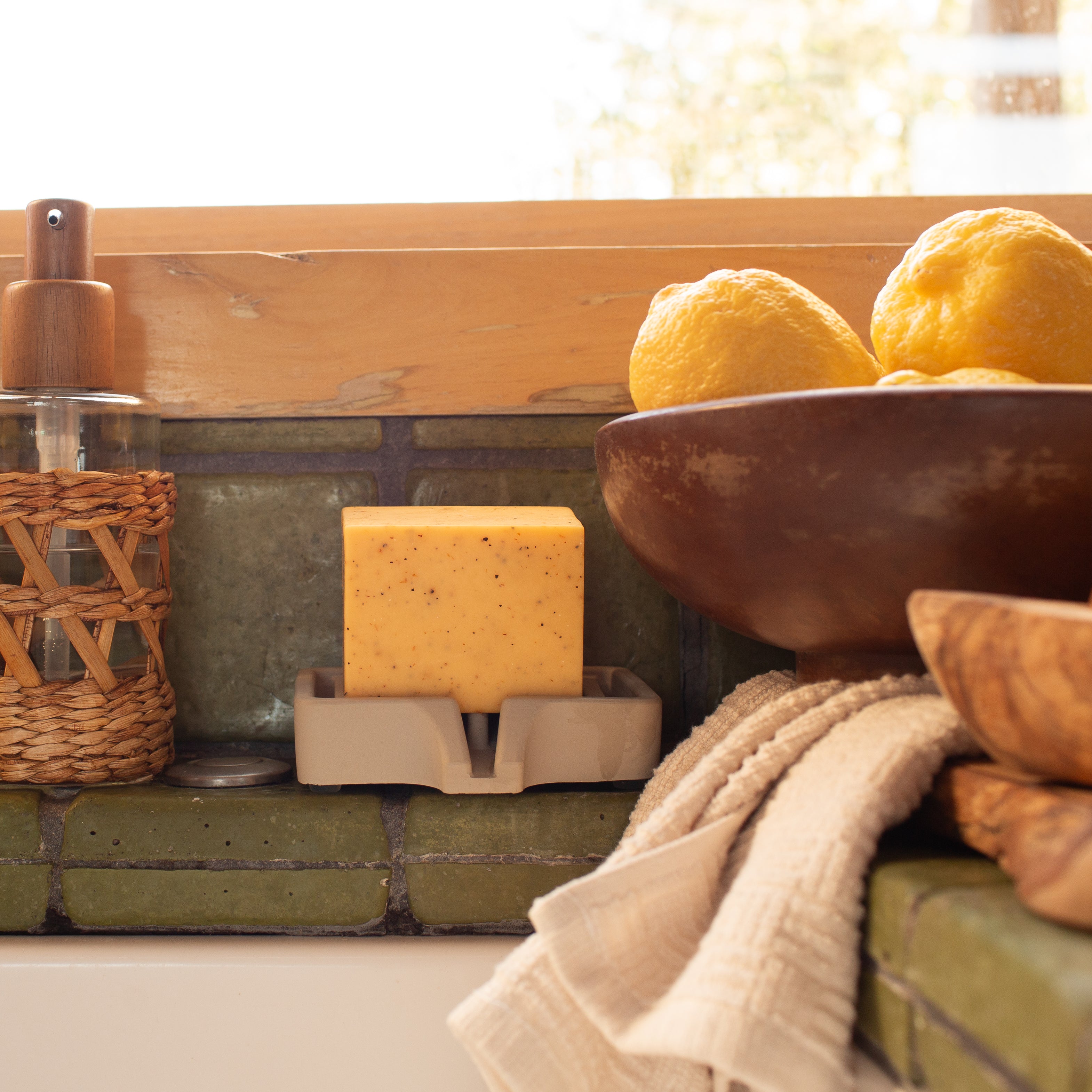Bar of Lemon Pine Solid Dish Soap next to lemons and a wooden bowl on a kitchen counter