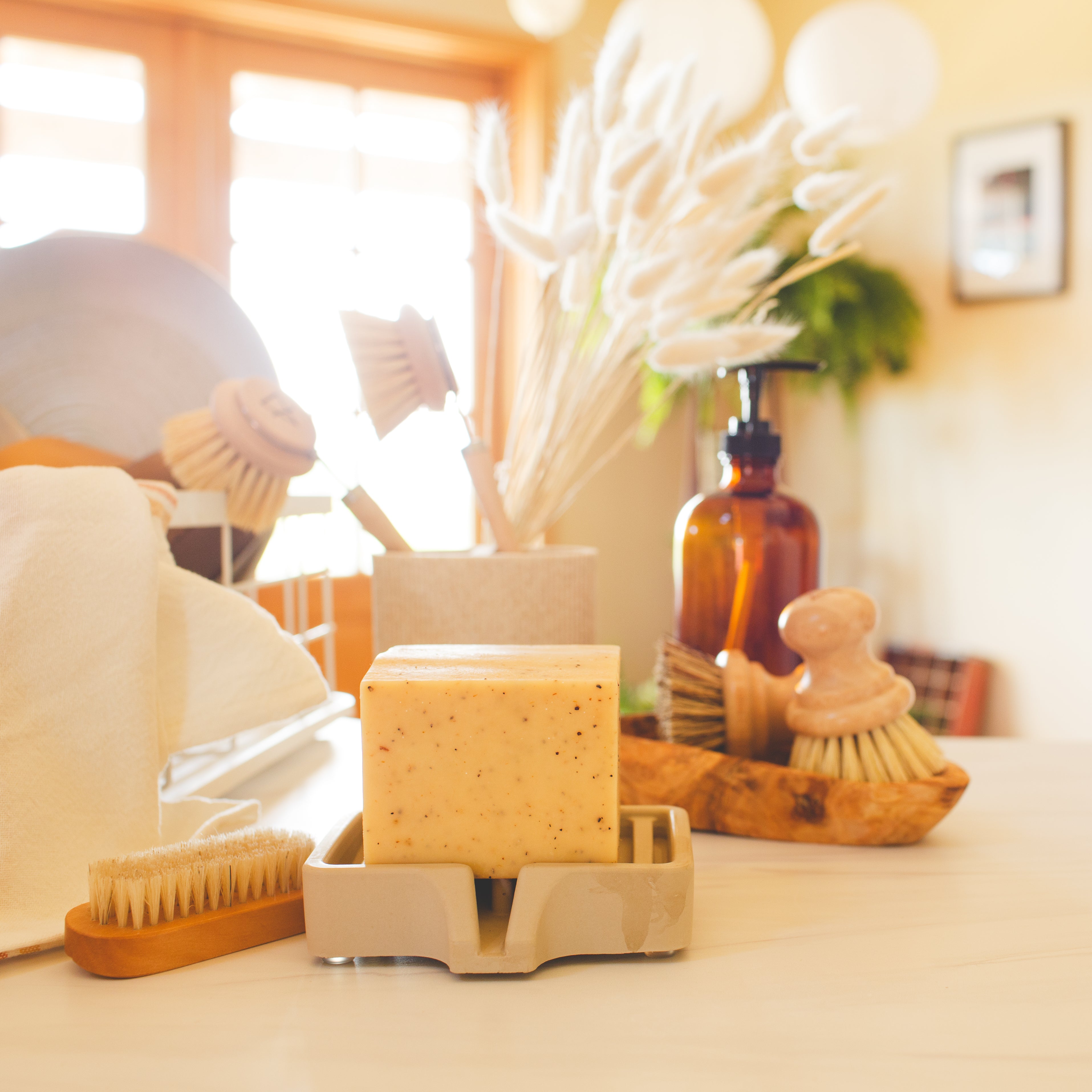 Lemon Pine Solid Dish Soap in a sunlit kitchen beside a vase of soft grasses and natural cleaning tools