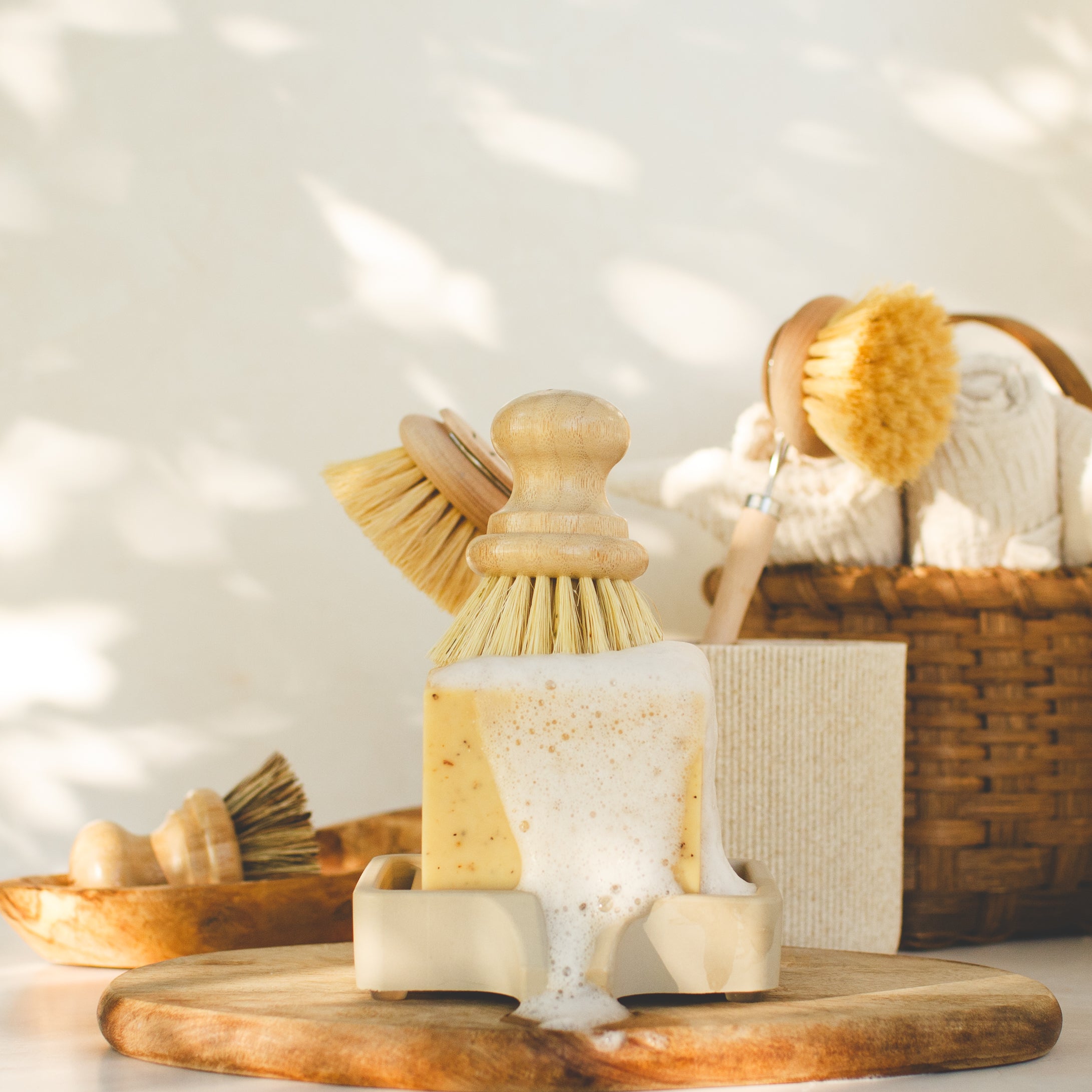 Lemon Pine Solid Dish Soap on a wood tray with compostable dish brushes and a sunny backdrop