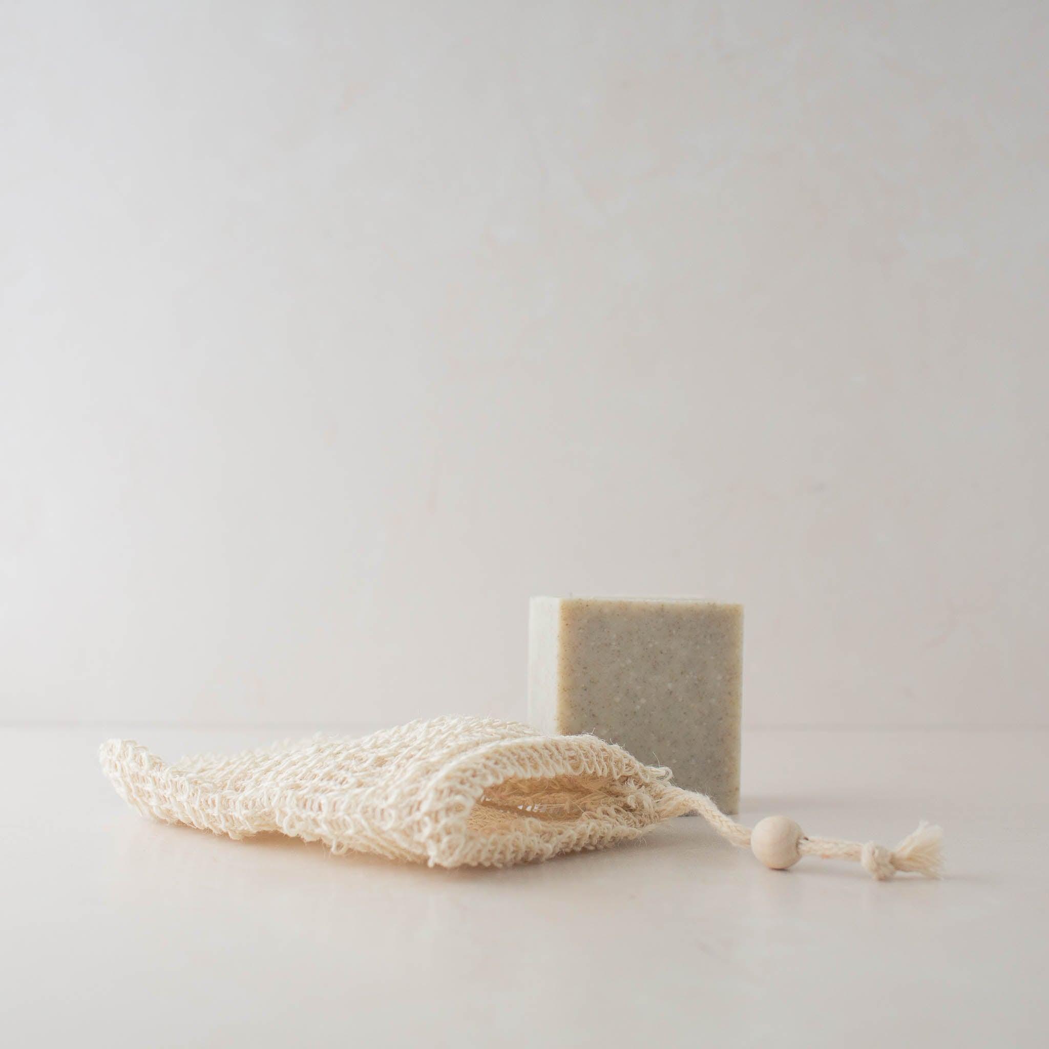 Compostable white woven sisal soap saver bag, shown with Scrub Bar Soap.