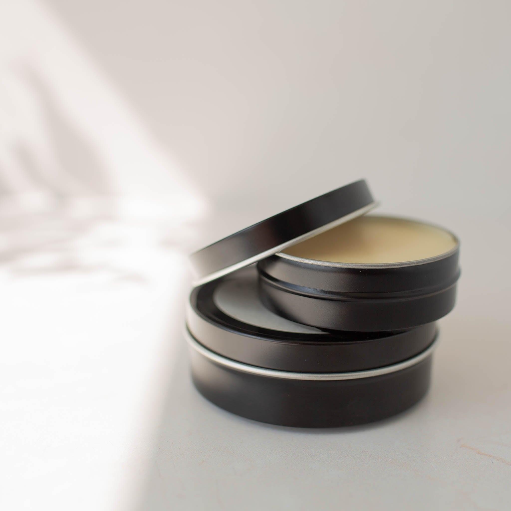 Stack of black tins of Relief Balm.